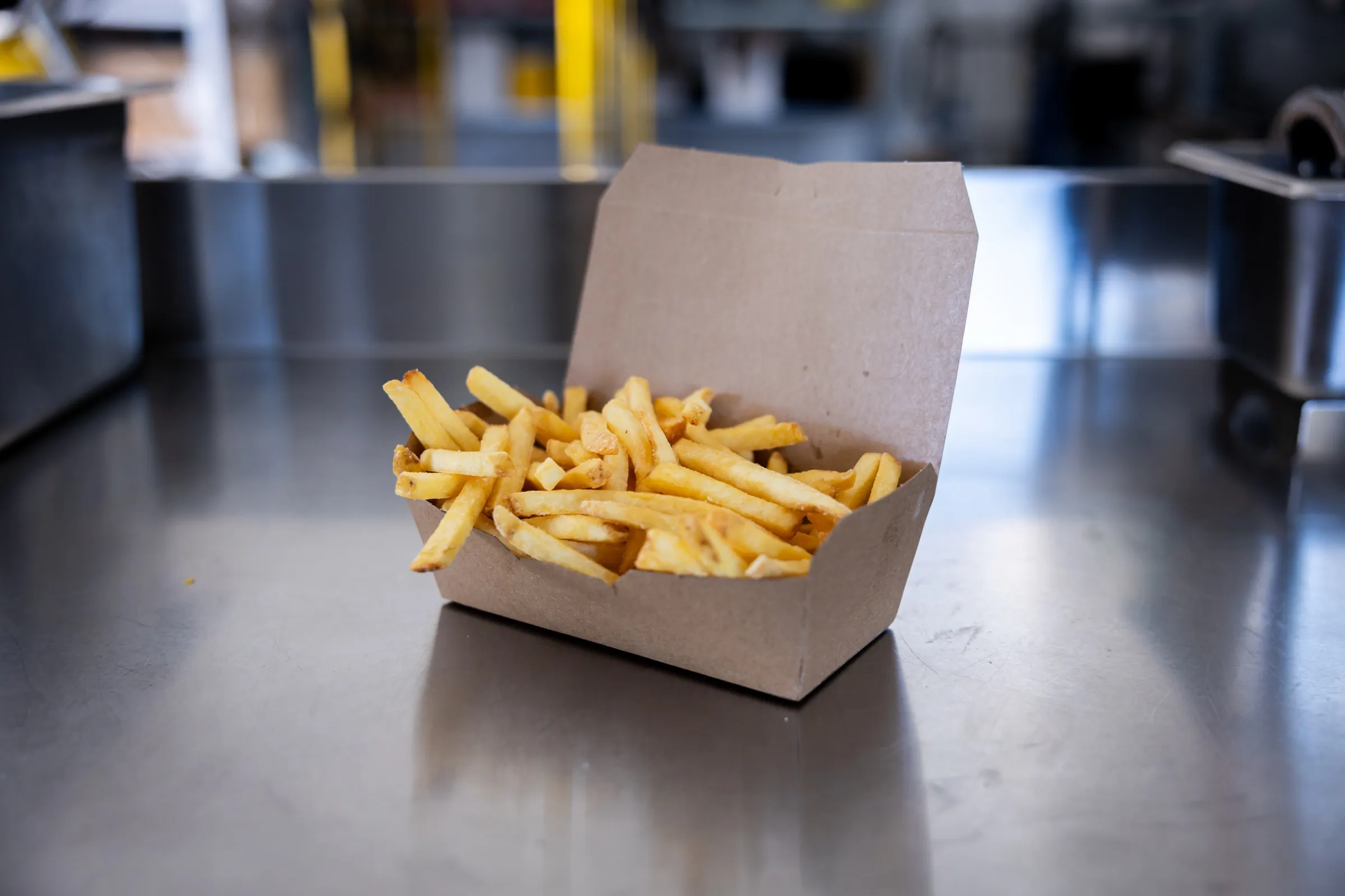 Fries i en papboks på et stålbord